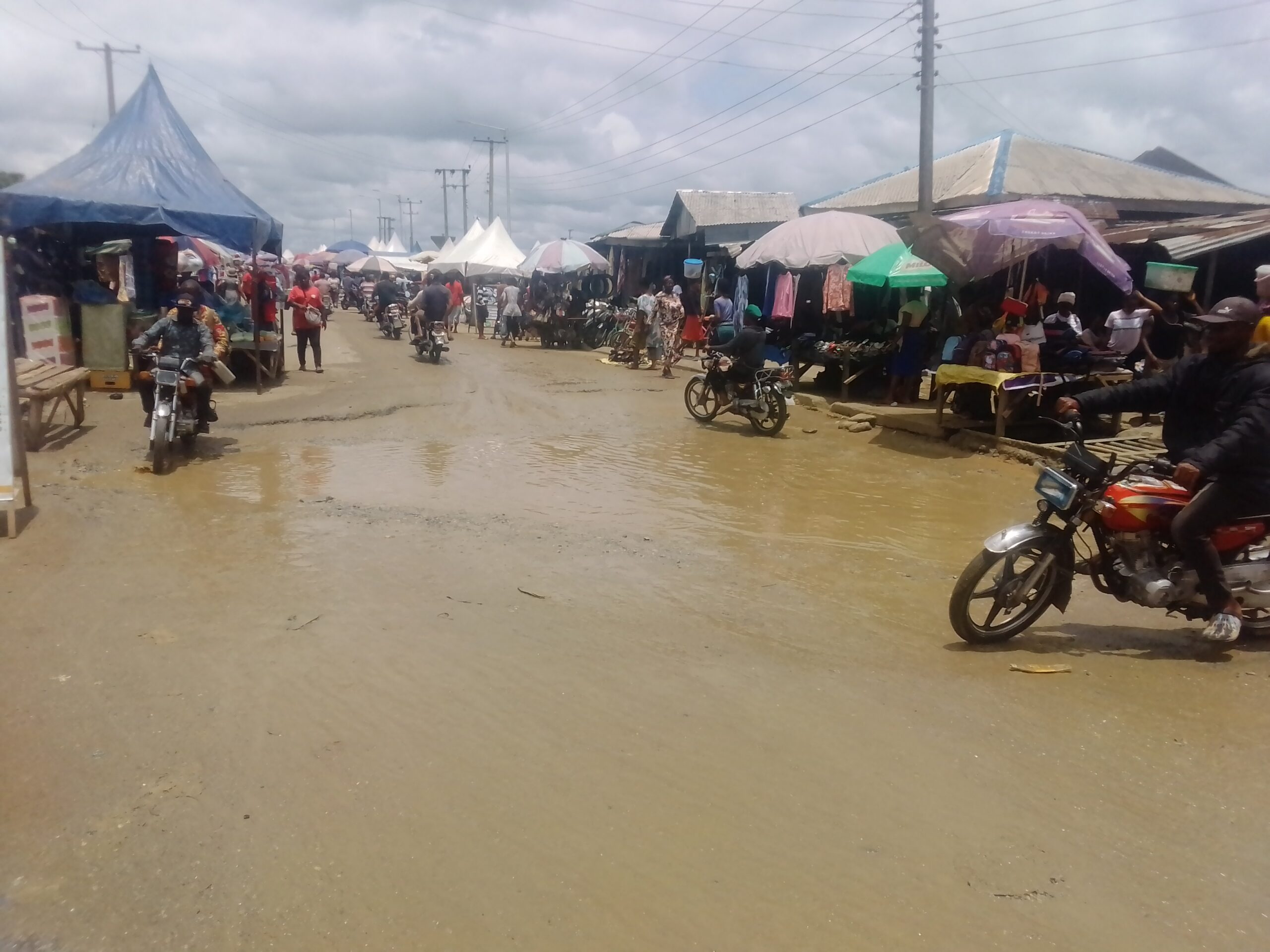 Transporters dodging flooded potholes in Idua market