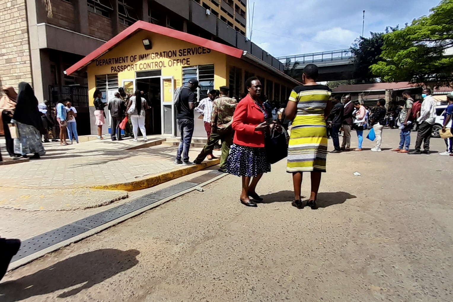 People wait outside the immigration office to process their documents and passport applications. Photo by Ngina Kirori